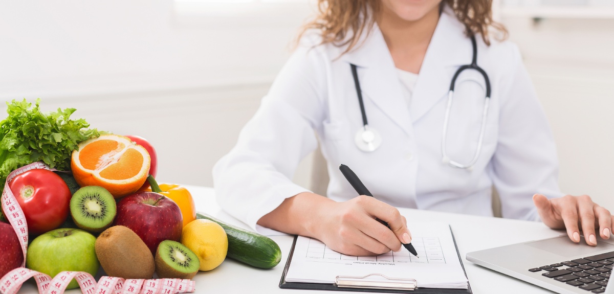 doctor writing diet plan on table and using laptop