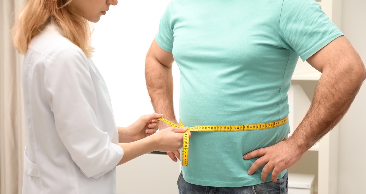 doctor measuring overweight man's waist