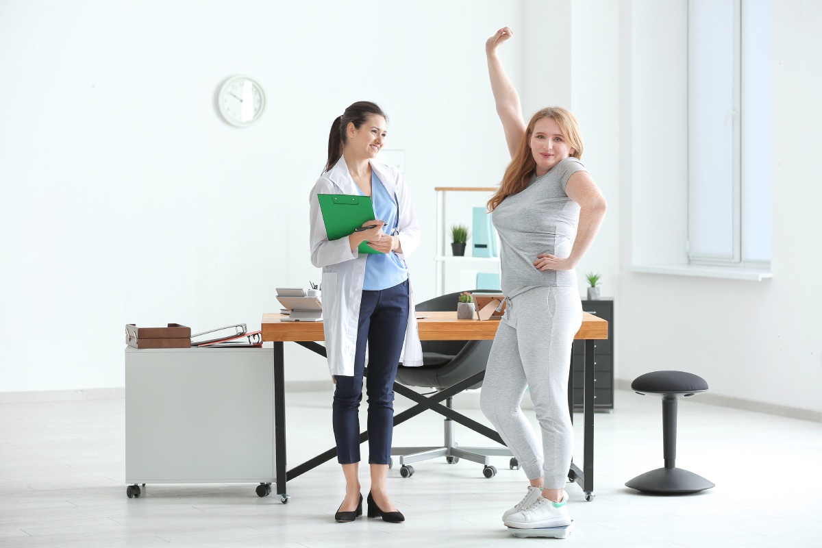 female doctor measuring weight of overweight woman