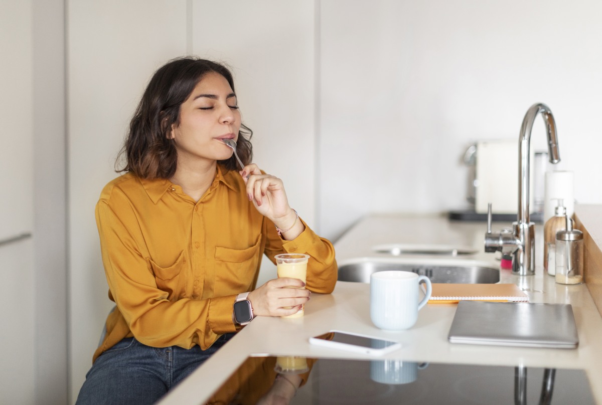 woman sitting at kitchen counter and eating pudding